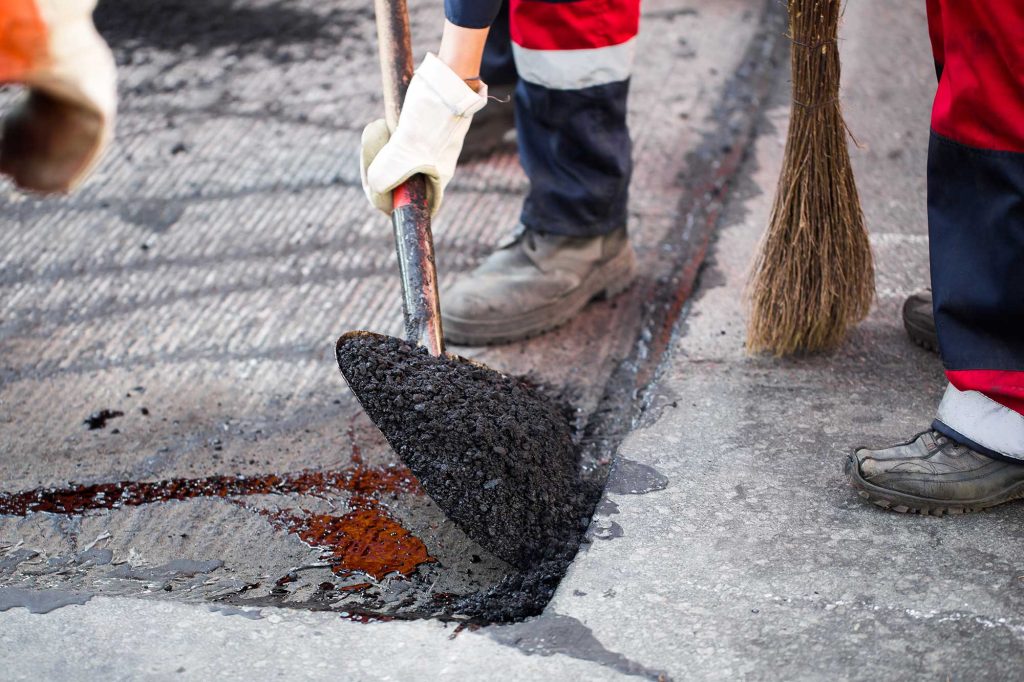 A pile of recycled asphalt in front of a construction truck, ready for use in a paving project.