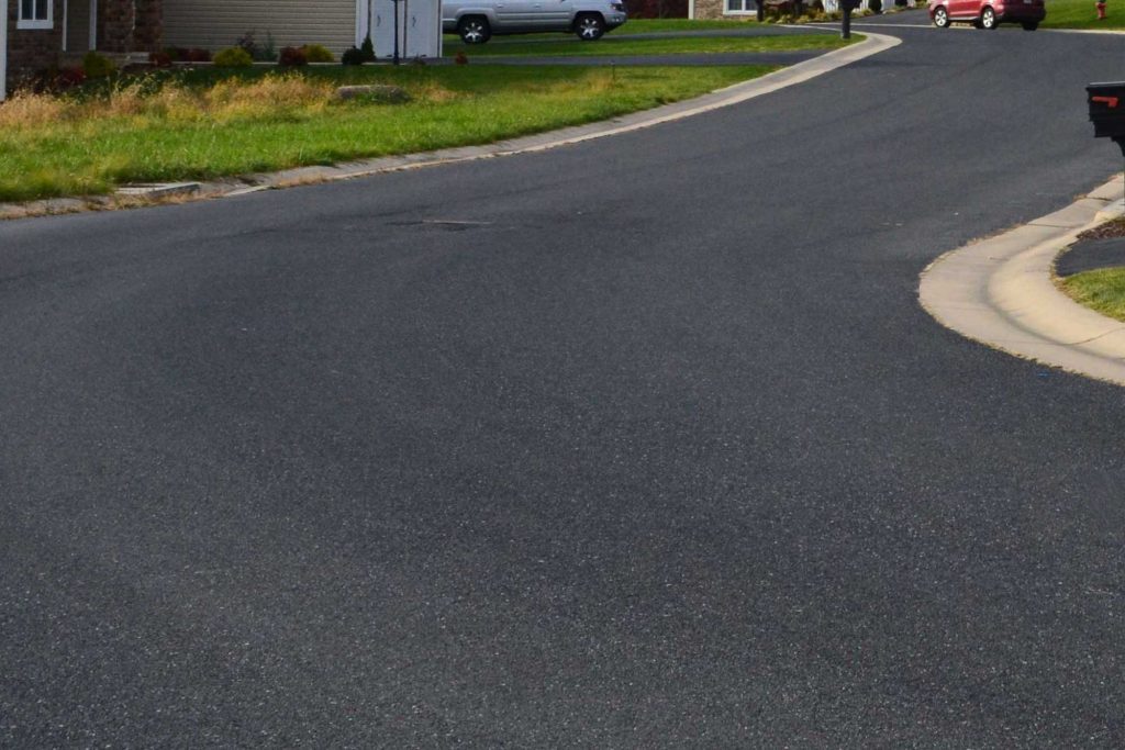 A newly completed residential paving project with a smooth asphalt driveway.